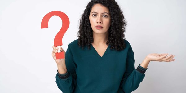 Woman holding a large red question mark with a confused expression.