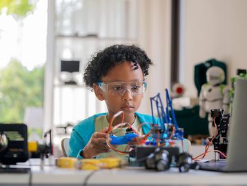 Young boy working on a robotics project with focused concentration.