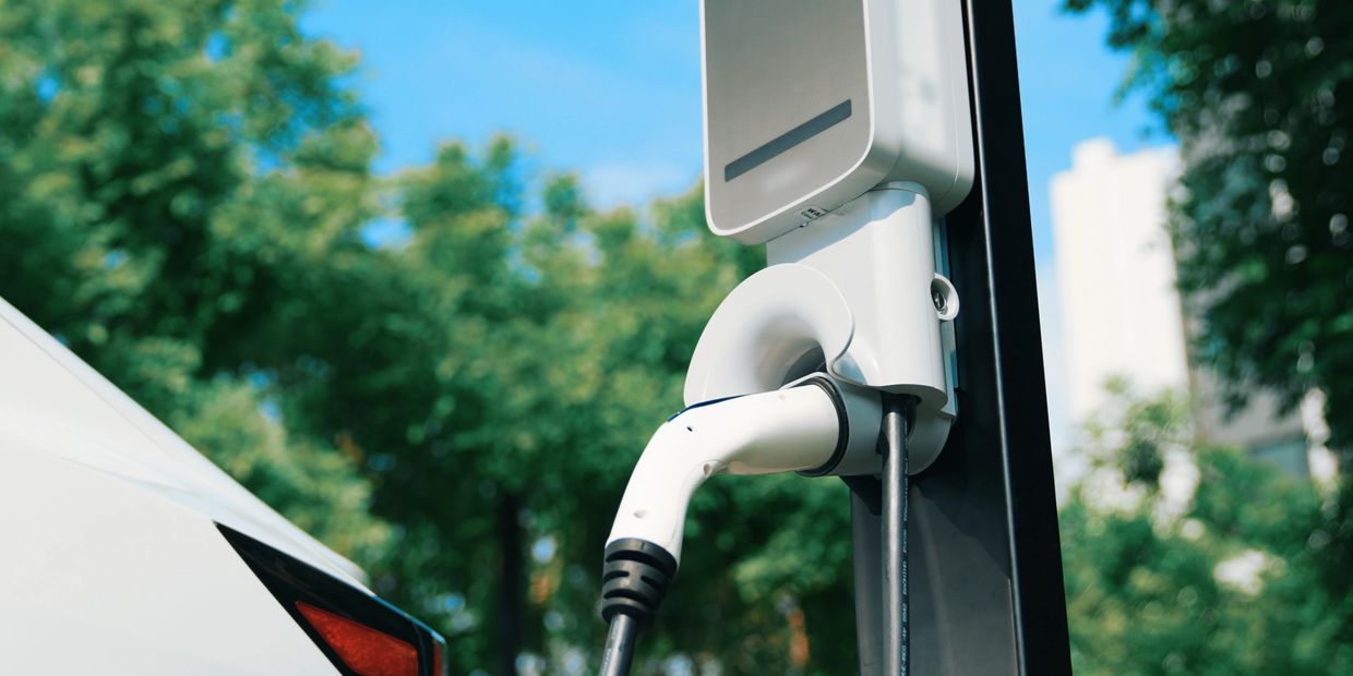 Electric vehicle charging at an outdoor station on a sunny day.