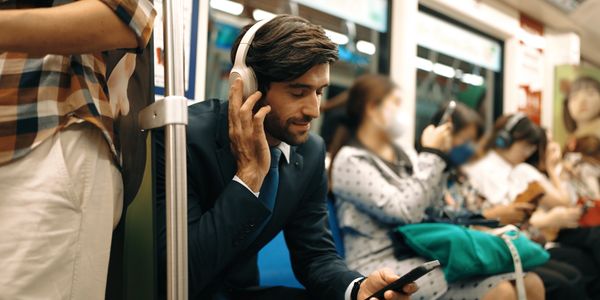 Man in suit enjoying music on headphones while commuting on subway.