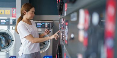 Woman using smart device in a laundromat.