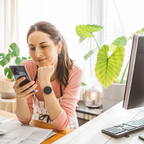 Woman looking at phone while sitting at desk.