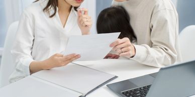 Young couple reviewing insurance paperwork together at a desk with a laptop and binder open