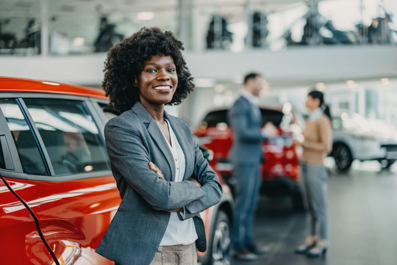 At the heart of the showroom stands a young African American woman, her dedication and passion for cars transforming the space into a hub of discovery and decision-making