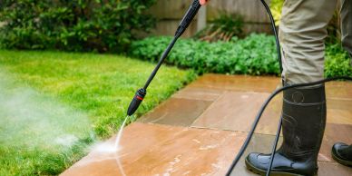Person pressure washing outdoor tiles.