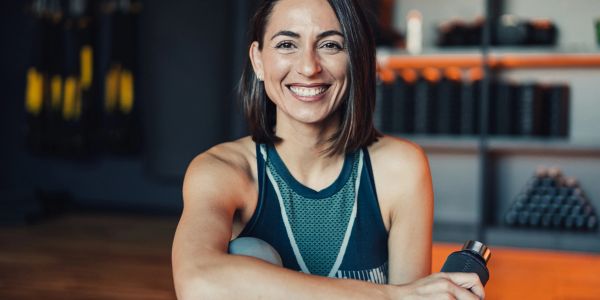 Smiling woman in workout clothes holding a water bottle.