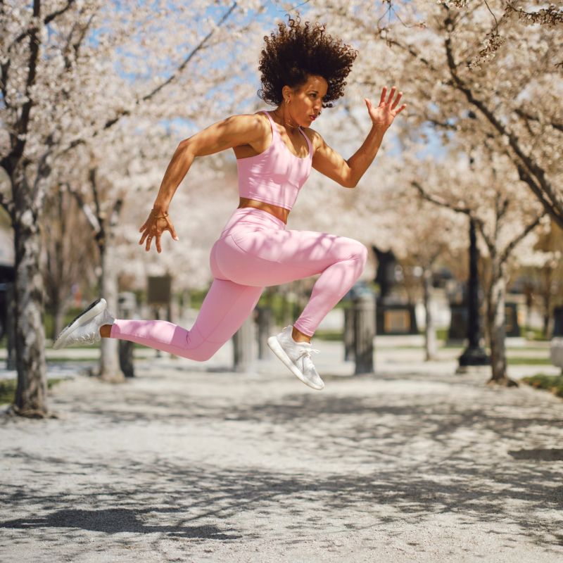 A woman athlete jumping among the cherry blossoms at the Utah State Capitol building for exercise in Salt Lake City, Utah USA.