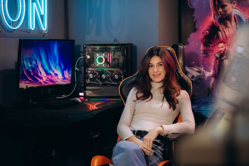 Fasionable Female Gamer Winning in Online Video Game on Computer. Portrait of Young Stylish Woman in Headphones Playing PvP Tournament with Other Players, Talking with Team on Microphone.