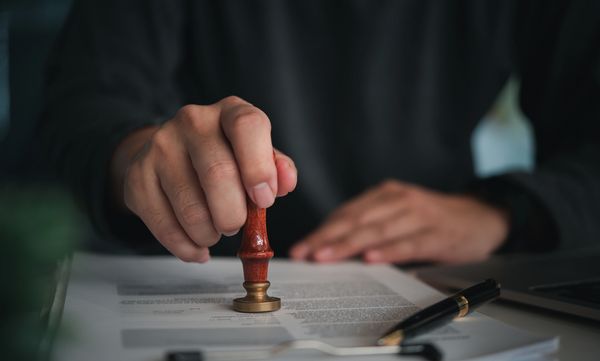 Person stamping a document with a wax seal.