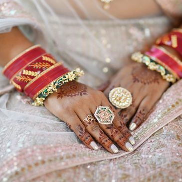 Bridal hands with henna, rings, and red bangles.
