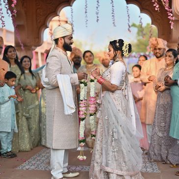 Indian couple exchanging flower garlands during wedding ceremony.