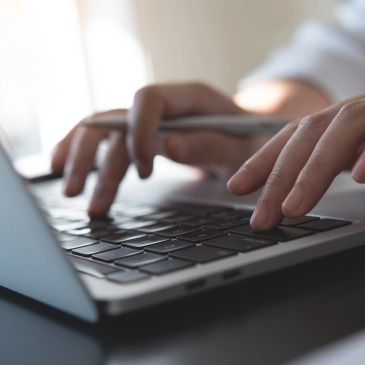 Person typing on a laptop keyboard.