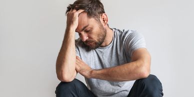 A man with a beard holding his head with mental stress.