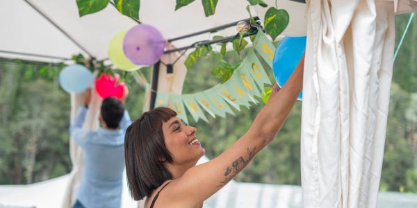 Two people decorating for a party with balloons and banners.