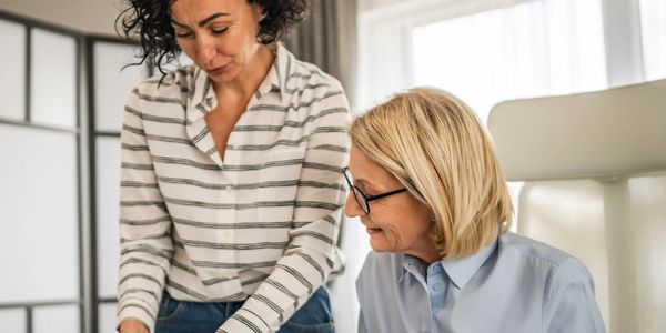 Two women collaborating over documents in a bright office.