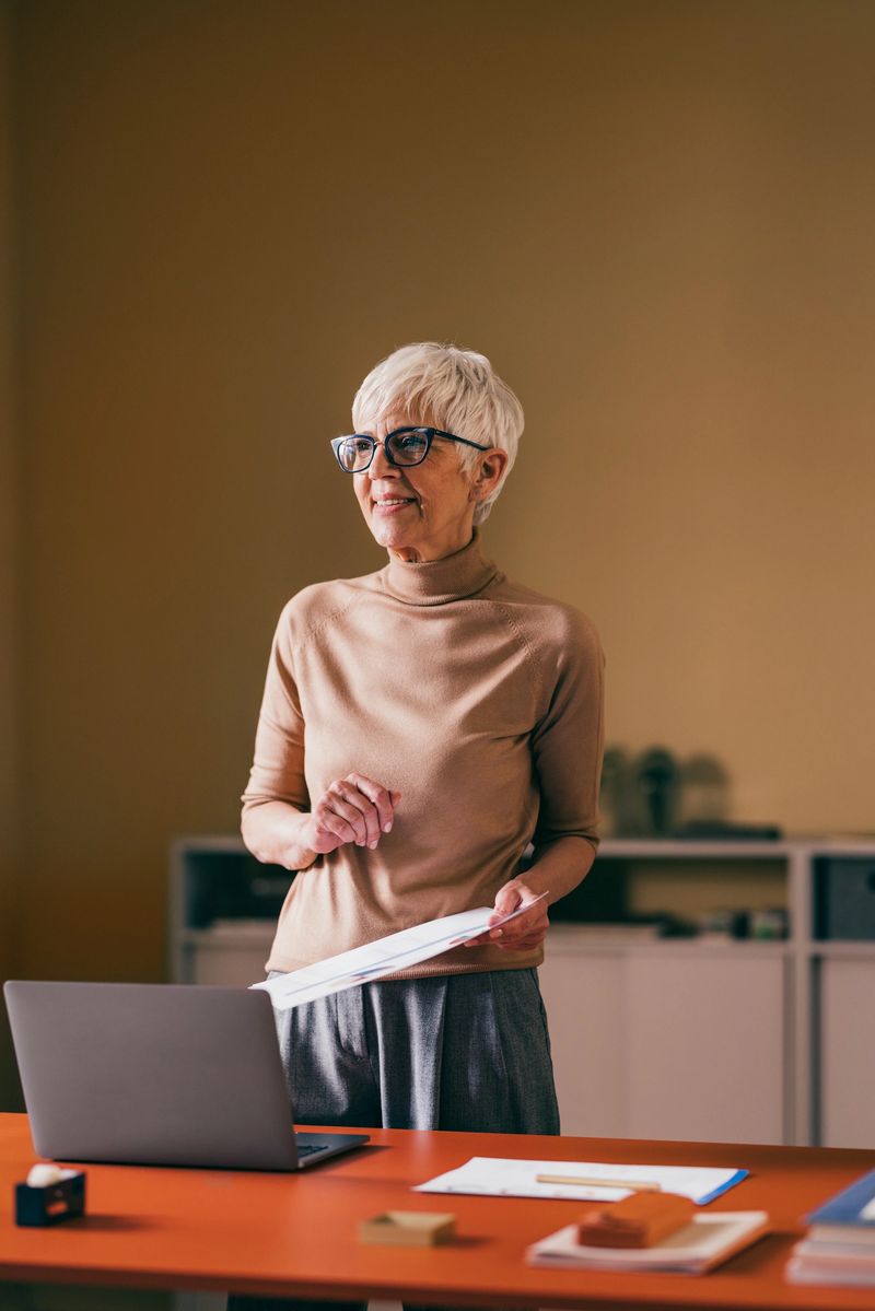 Experienced senior businesswoman reviews paperwork with focus and determination at her organized office workspace.