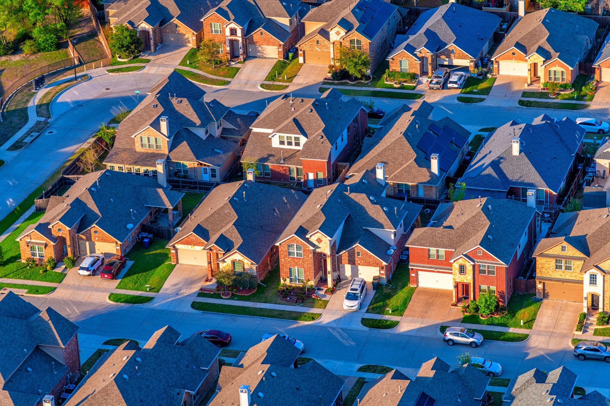 Aerial view of a suburban neighborhood with houses and cars.