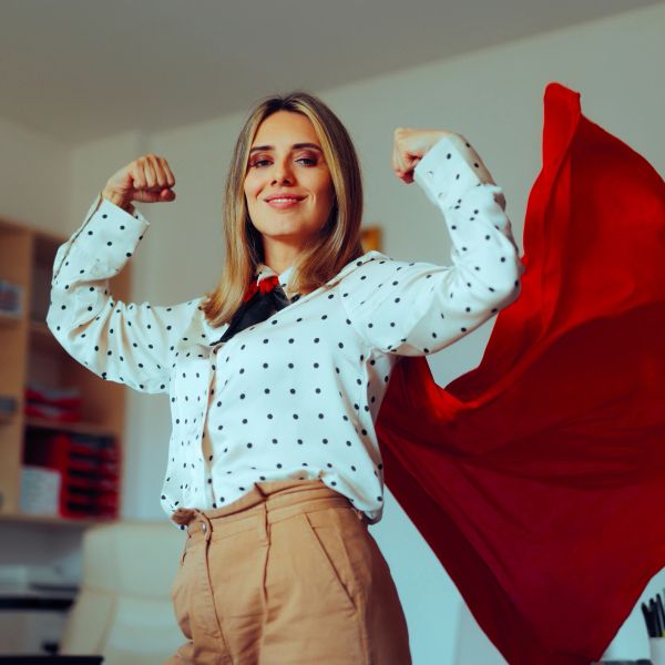 Confident woman posing with red cape and flexed arms.