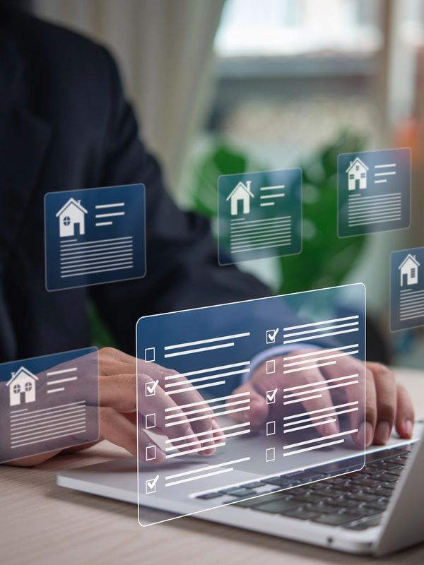 Businessman using laptop with digital real estate interface overlays.