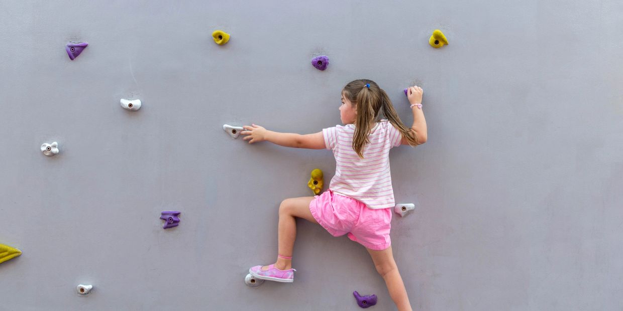 Young girl climbing a colorful indoor rock wall.