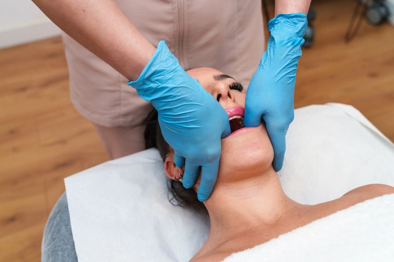 Therapist performs precise TMJ therapy on relaxed patient's jawline