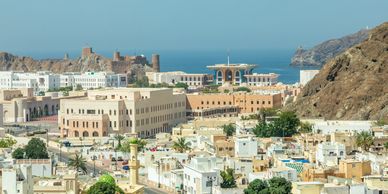 Muscat, Oman ancient city buildings with sea in the background.