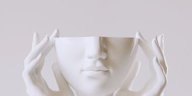A white sculpture of a face held by two hands, missing the upper head.