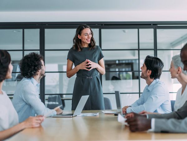 A confident woman leads a business meeting with engaged colleagues around a table.