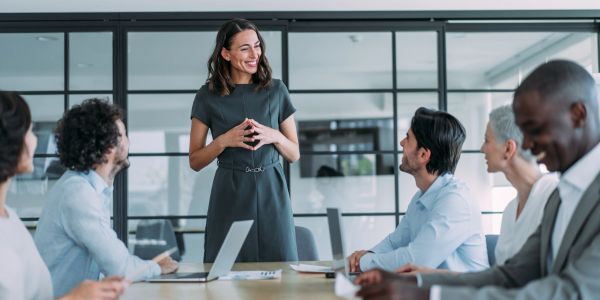 A woman confidently leads a business meeting with engaged colleagues.