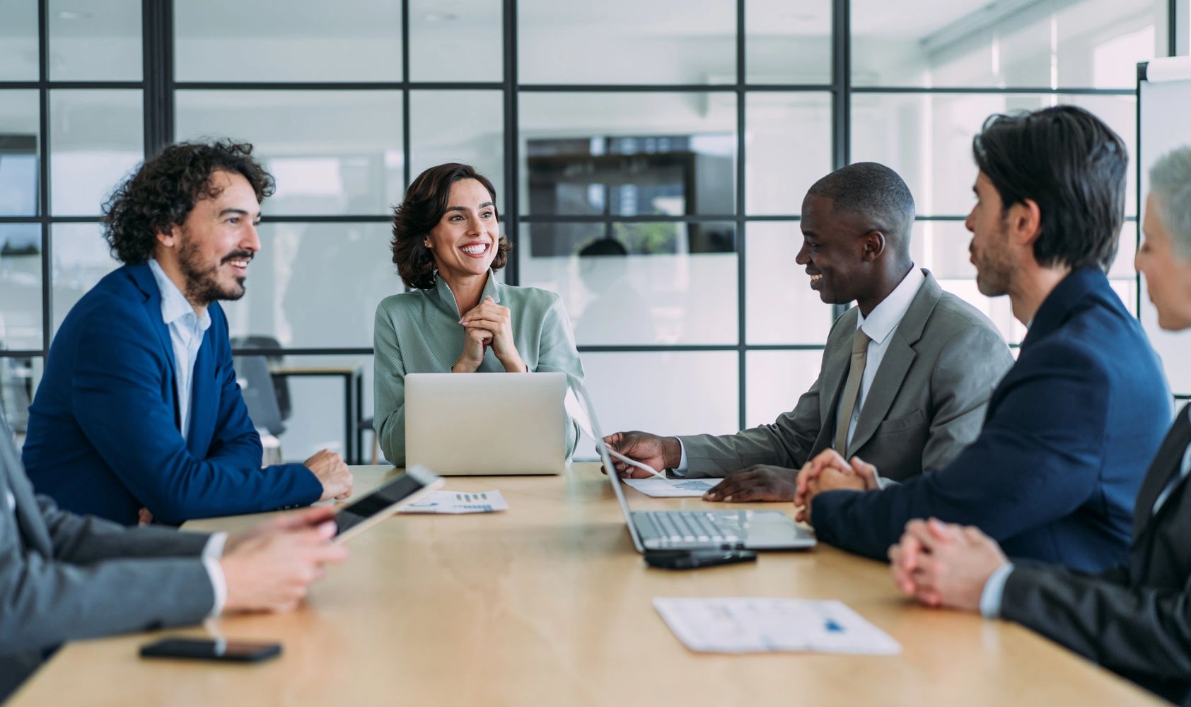 Diverse professionals smiling and discussing ideas around a conference table.
