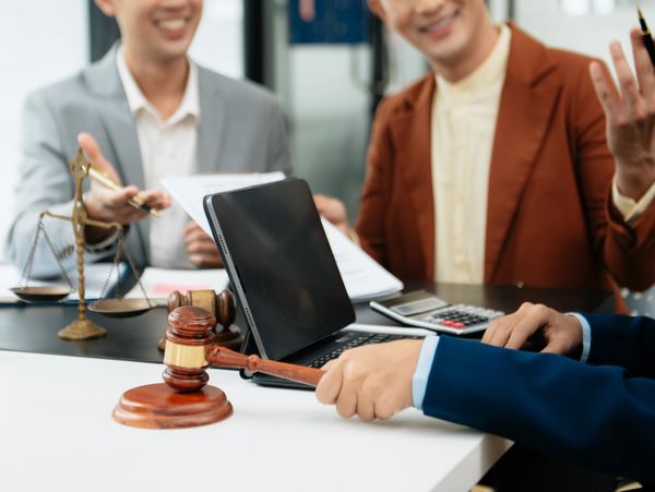 Legal professionals discussing a case with a gavel and scales of justice on the table.