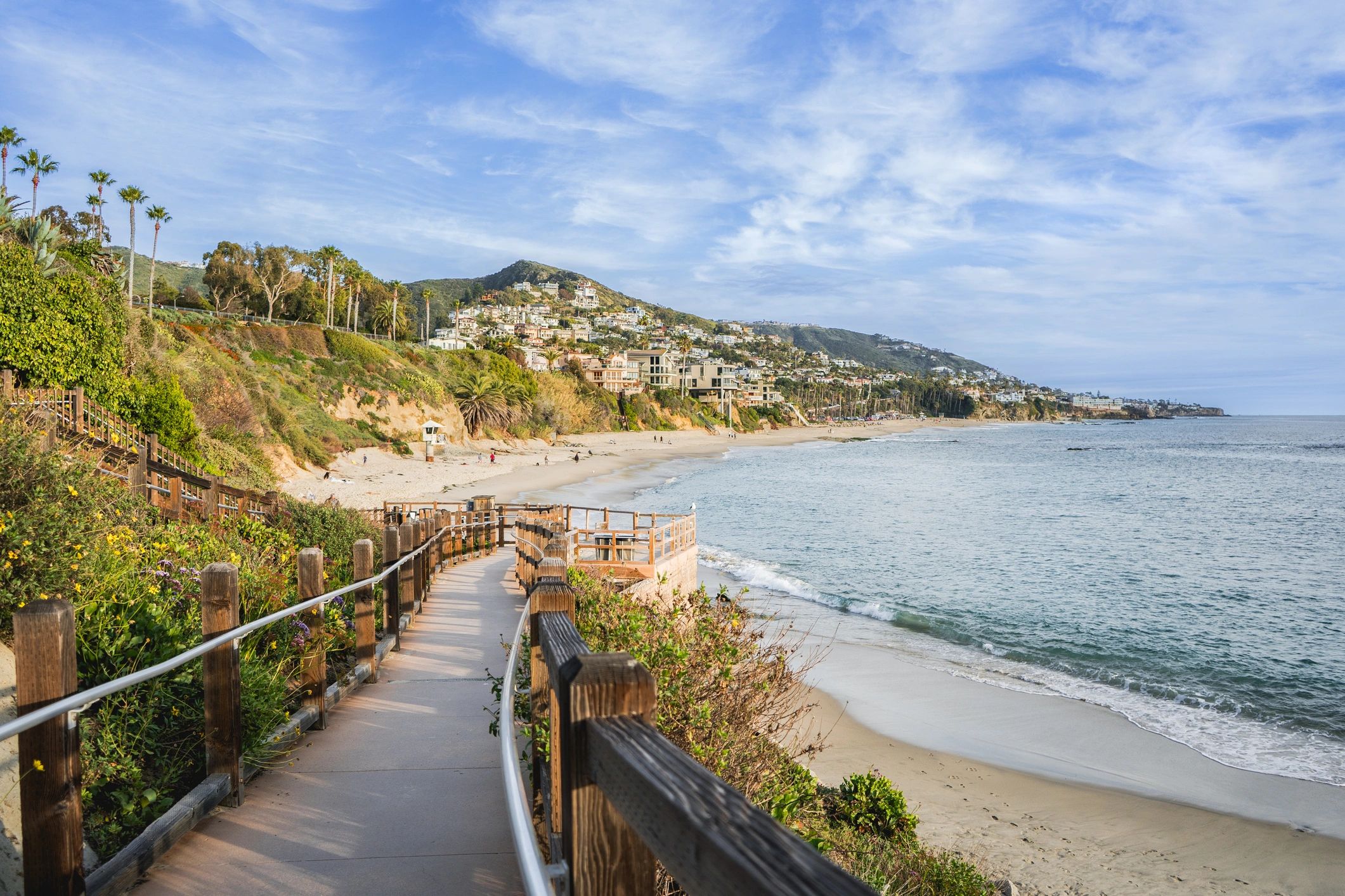 A scenic coastal walkway overlooking a sandy beach and ocean.