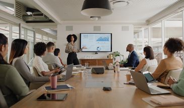Woman presenting annual report to colleagues in a modern conference room.