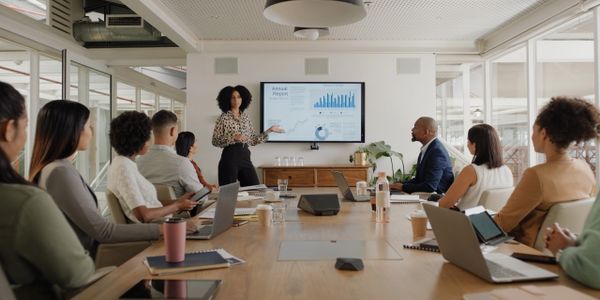 A woman presents data to colleagues in a modern conference room.