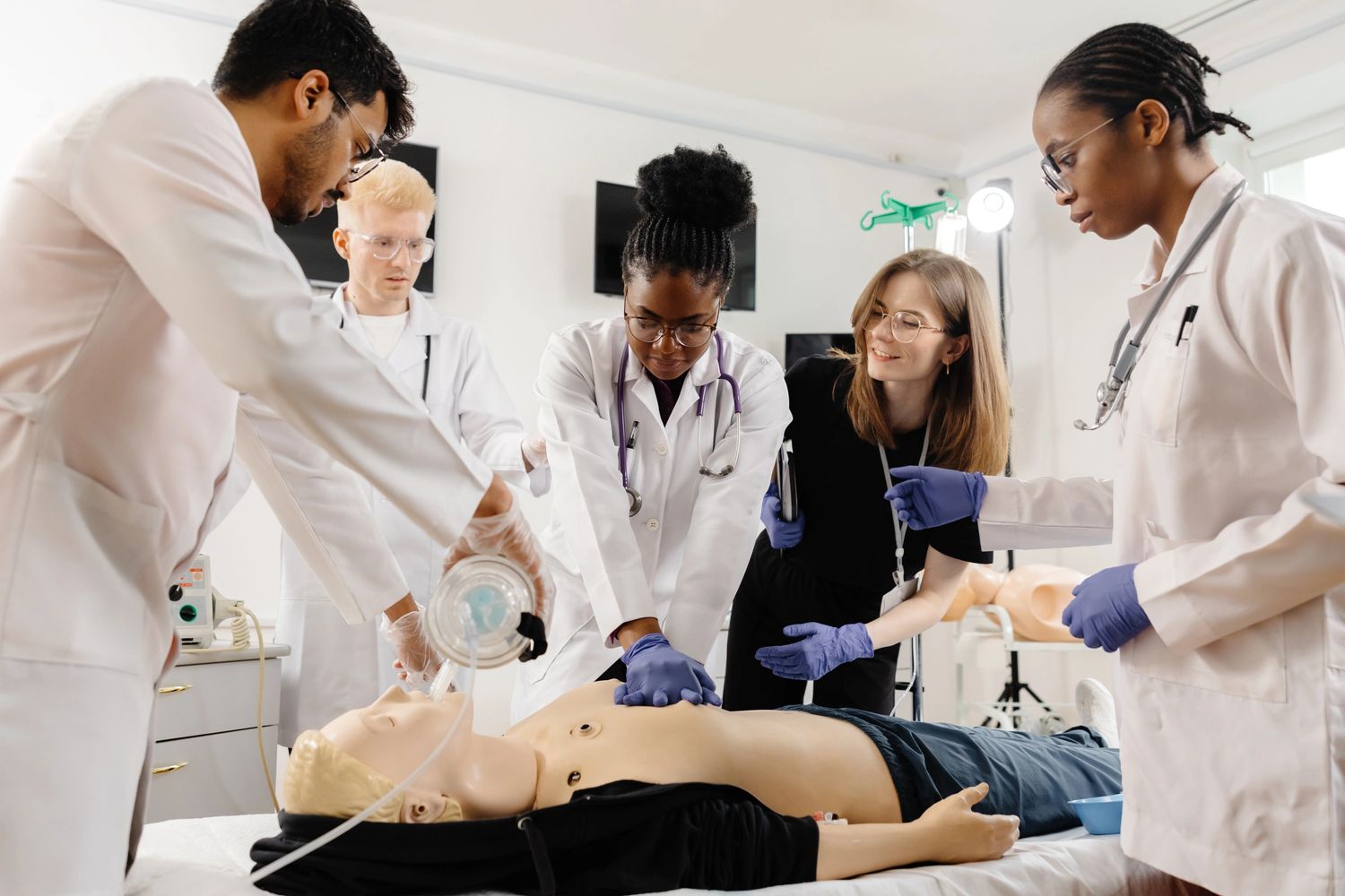 Medical students practicing CPR on a training mannequin in a clinical setting.