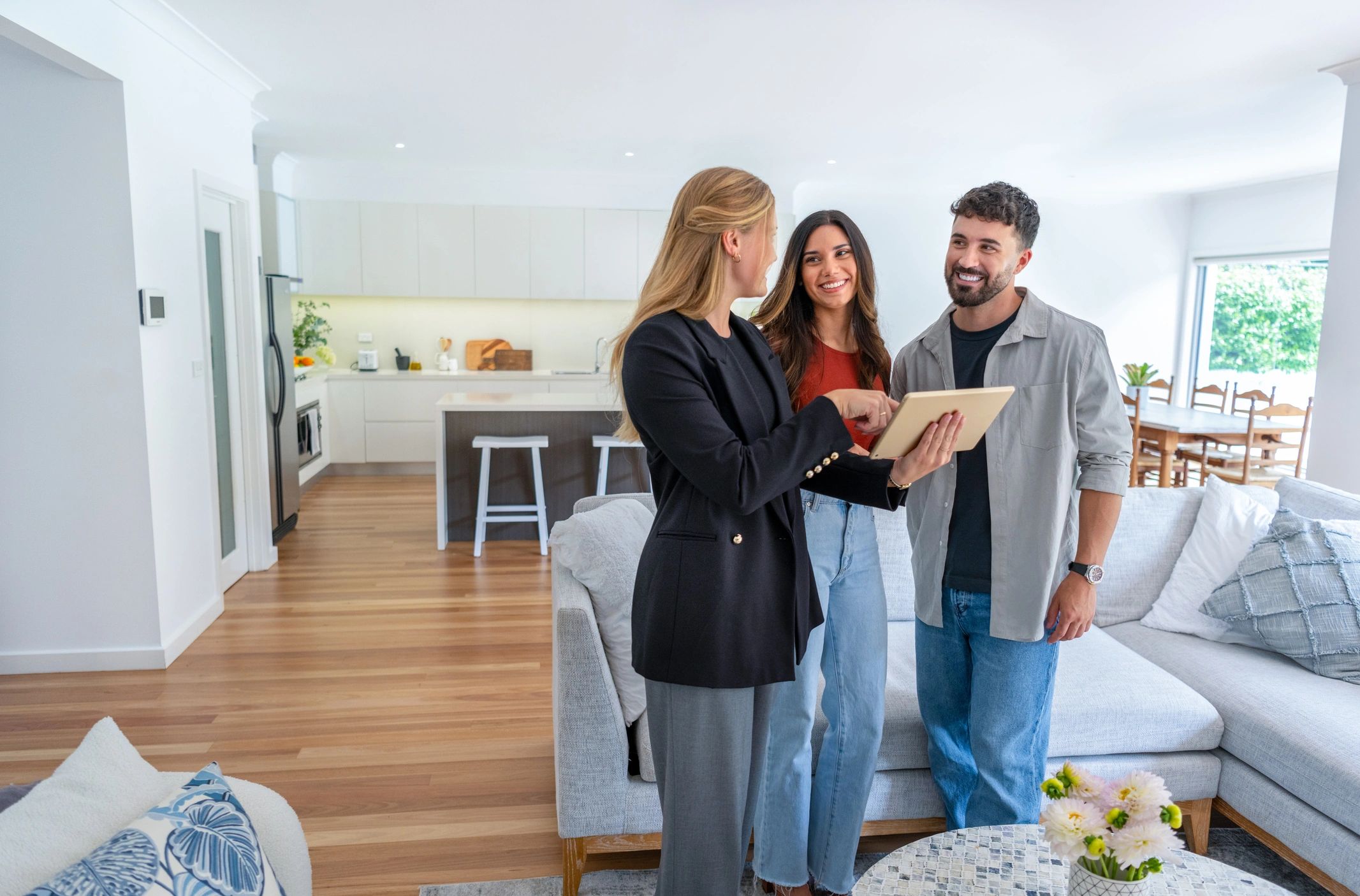 Real estate agent showing a couple a home on a tablet.