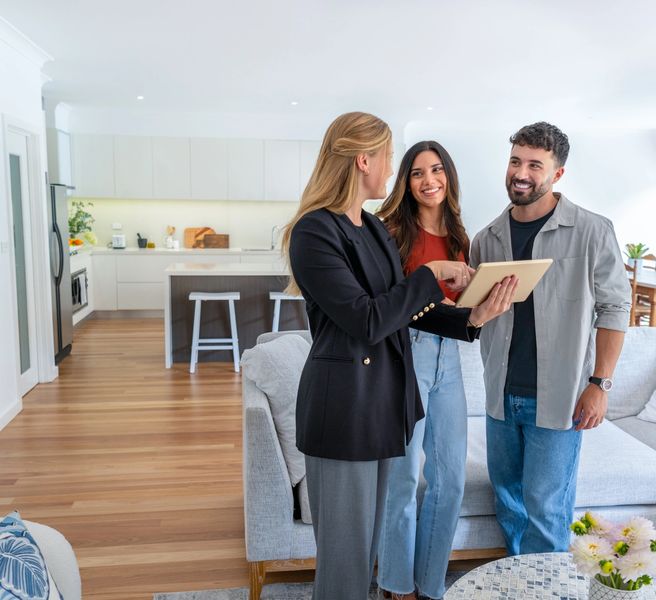 Real estate agent showing a tablet to a couple in a modern home.