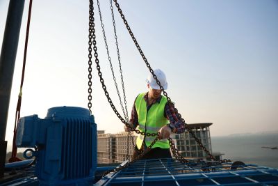 Worker securing chains on construction site.