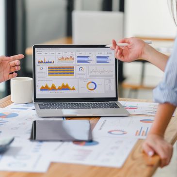 Hands collaborating over strategy documents and dashboards, representing the HERON System framework.