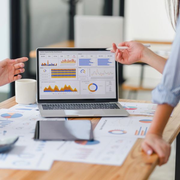 People discussing sales data shown on a laptop screen.