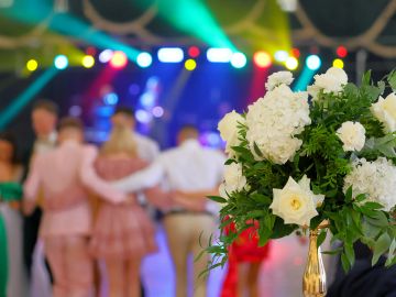 A floral centerpiece with white flowers at a vibrant party scene.