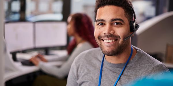 Smiling customer service representative wearing a headset in an office.
