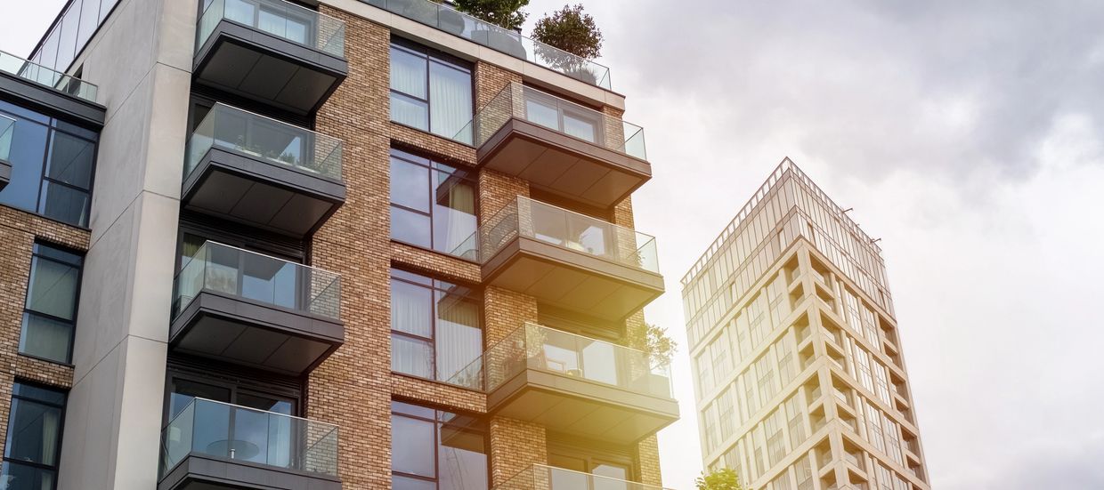 Modern apartment buildings with glass balconies under a cloudy sky.