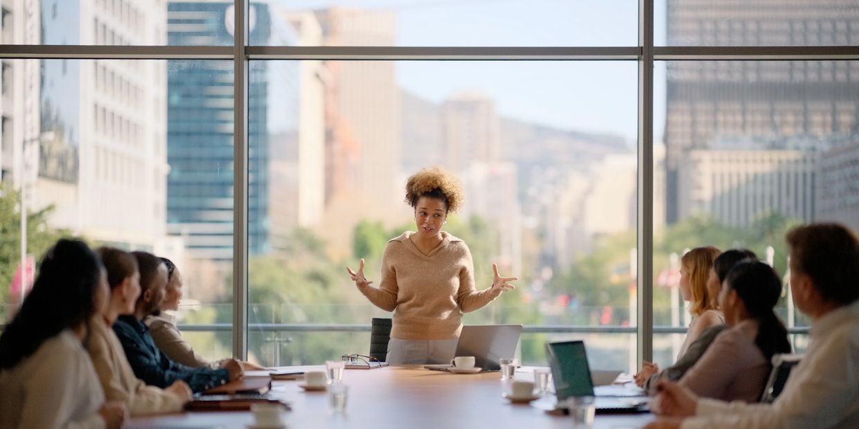 Woman leading a business meeting with attentive colleagues in a modern office.