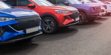 A parking lot filled with various cars under a pinkish sunset sky.