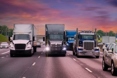 Semi trucks on the freeway in traffice hour with a sunset in the background