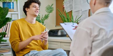 Young man in yellow sweater has a counseling session with a therapist.