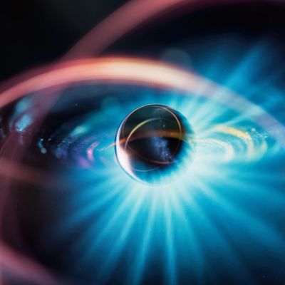 A glowing orb surrounded by colorful light trails on a dark background.