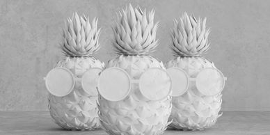 Three pineapples with blue tops wearing round glasses against an orange background.