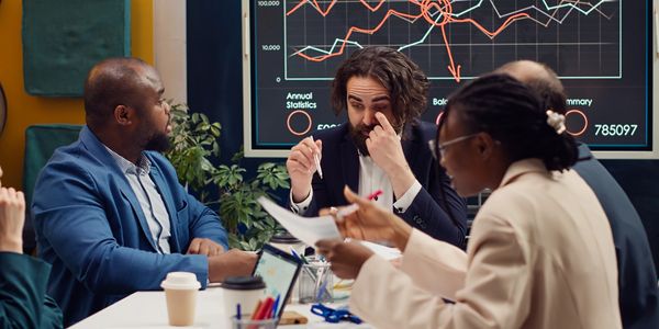 Business team discussing data with charts on screen during a meeting.